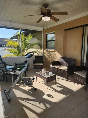 Screened outdoor living area featuring a ceiling fan with integrated lighting, textured wall finish, and a large sliding glass door