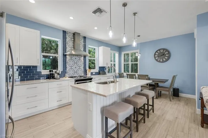 Modern kitchen featuring white cabinetry, light-toned wood-finish flooring, and a central island with counter seating