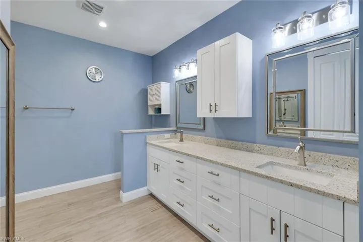 Dual vanity with white cabinetry, speckled countertops, and undermount sinks