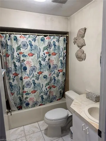 Full bathroom featuring tile patterned floors, vanity, shower / bath combination with curtain, and toilet
