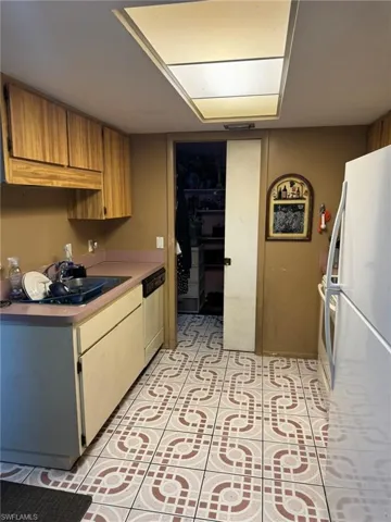 Kitchen featuring dishwasher, white fridge, light tile patterned floors, and sink