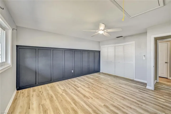 Unfurnished bedroom featuring light wood finished floors, attic access, ceiling fan, and a closet