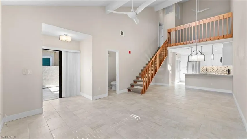 Unfurnished living room with beam ceiling and high vaulted ceiling