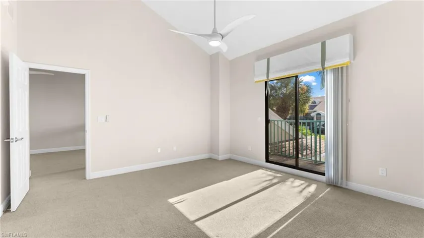 Spare room with ceiling fan, carpet floors, and high vaulted ceiling