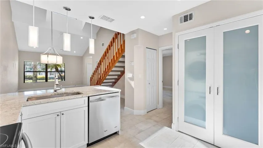 Kitchen featuring light stone counters, stainless steel dishwasher, sink, range, and white cabinetry