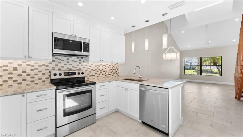 Kitchen featuring white cabinets, kitchen peninsula, sink, and appliances with stainless steel finishes
