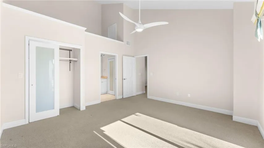 Unfurnished bedroom featuring carpet, ceiling fan, high vaulted ceiling, and a closet