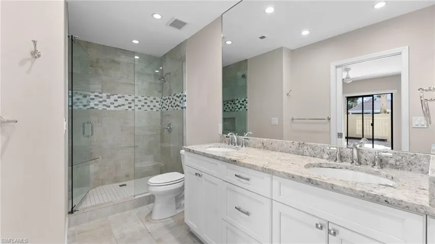 Bathroom with tile patterned floors, vanity, toilet, and a shower with shower door