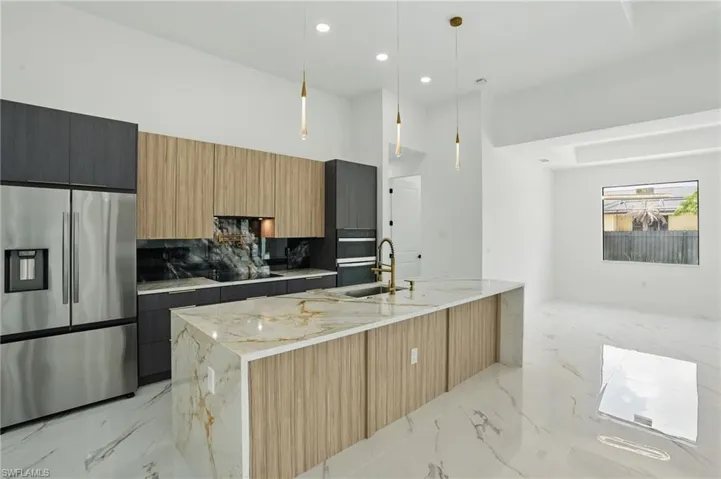 Kitchen with stainless steel fridge with ice dispenser, light marble finish floors, a sink, modern cabinets, and black electric cooktop