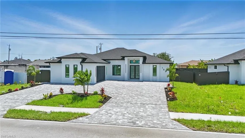 French provincial home featuring stucco siding, decorative driveway, and roof with shingles