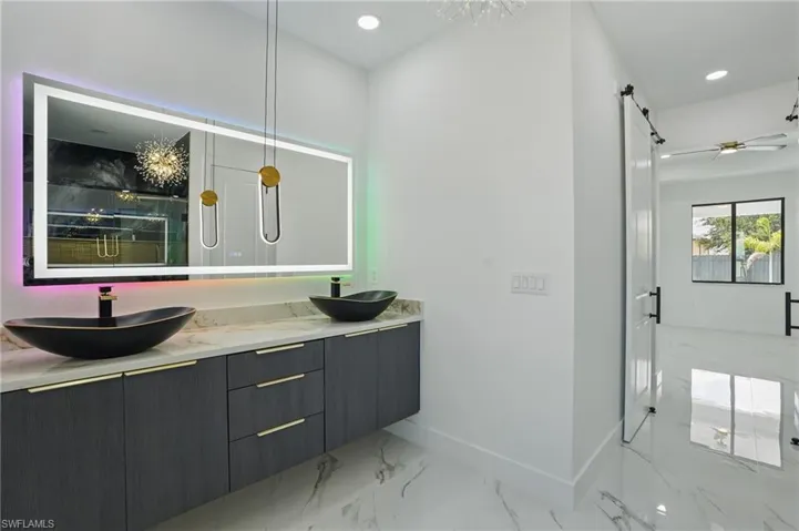 Bathroom featuring double vanity, a marble finish shower, marble finish flooring, baseboards, and recessed lighting