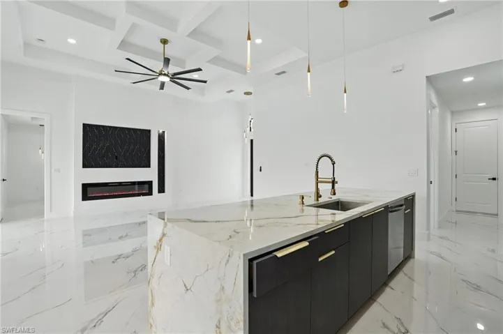 Kitchen with a sink, open floor plan, coffered ceiling, a center island with sink, and dark cabinets