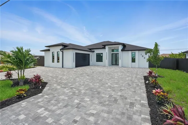 View of front of property featuring decorative driveway, stucco siding, and a garage