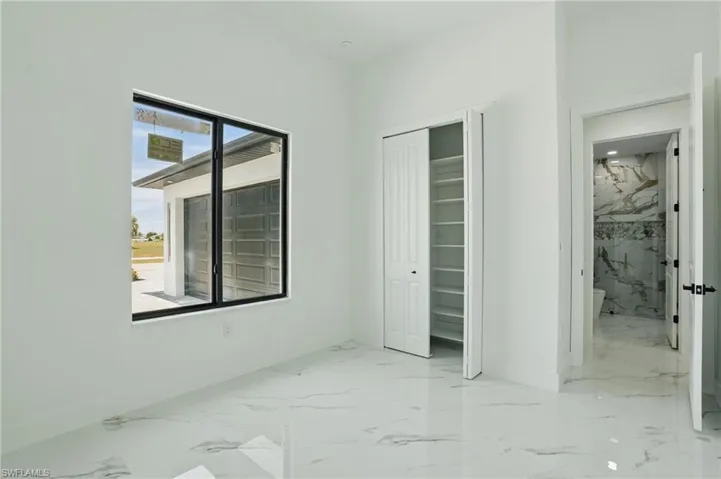Unfurnished bedroom featuring marble finish floors, baseboards, and a closet
