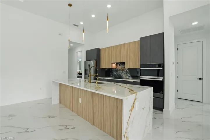 Kitchen with oven, modern cabinets, a sink, light marble finish flooring, and recessed lighting