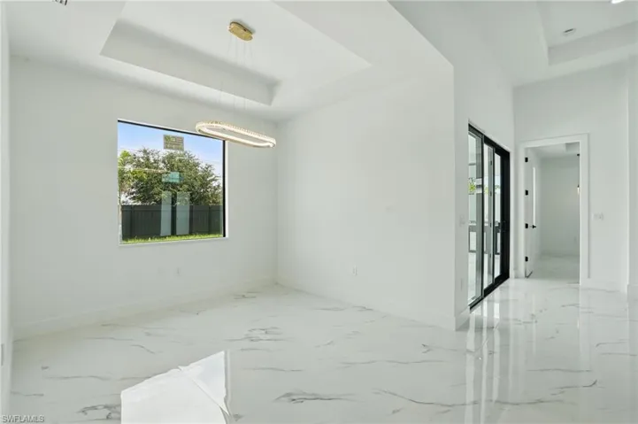 Unfurnished room featuring a tray ceiling, baseboards, and marble finish flooring