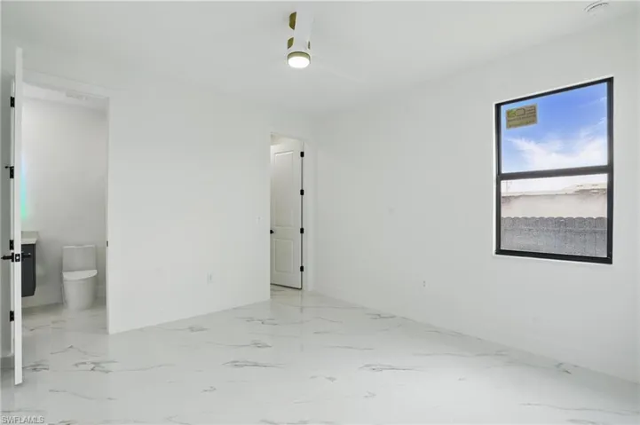 Unfurnished room featuring ceiling fan, baseboards, and light marble finish flooring