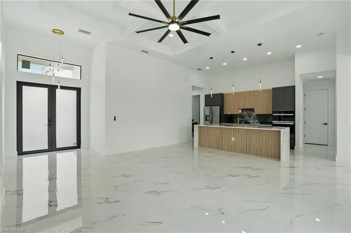 Kitchen featuring a towering ceiling, open floor plan, modern cabinets, recessed lighting, and stainless steel fridge with ice dispenser