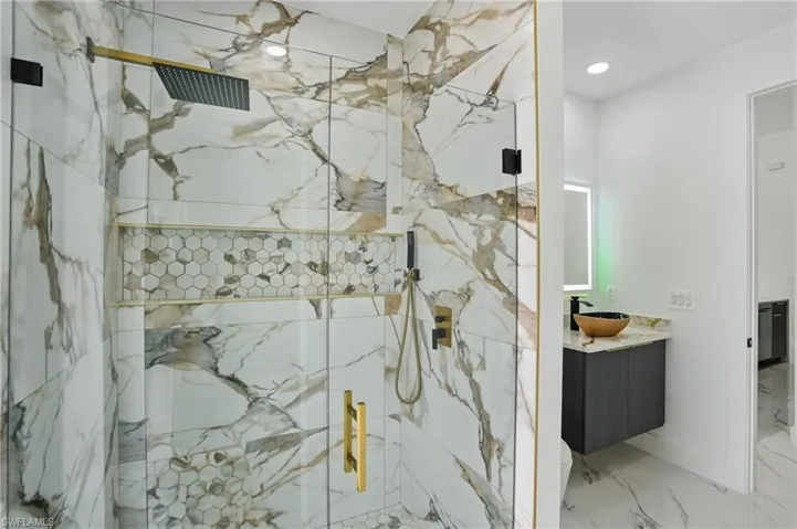 Full bath with vanity, a marble finish shower, marble finish flooring, toilet, and recessed lighting