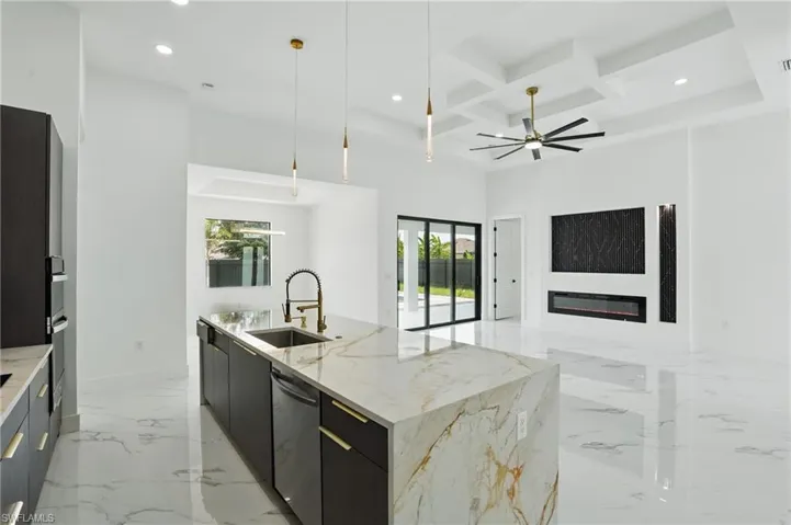 Kitchen featuring stainless steel dishwasher, a sink, modern cabinets, recessed lighting, and a high ceiling