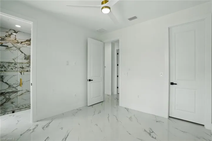 Unfurnished bedroom featuring marble look tiles, baseboards, and ceiling fan