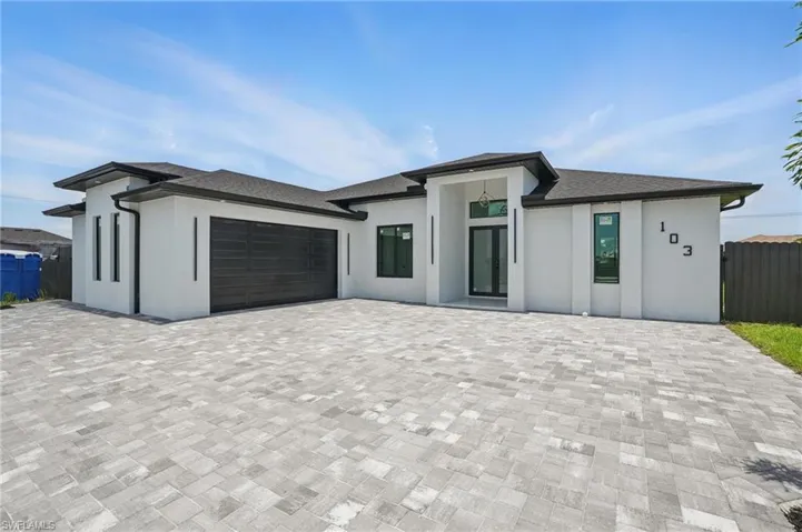 View of front of property with stucco siding, a garage, and decorative driveway