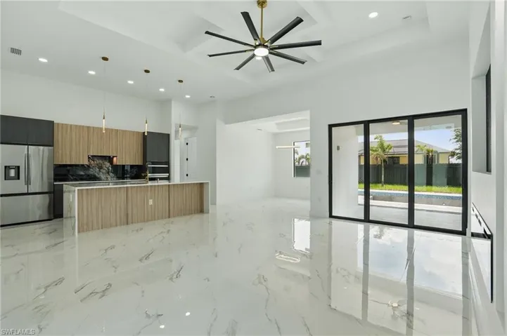 Kitchen with stainless steel fridge, open floor plan, recessed lighting, modern cabinets, and a kitchen island with sink