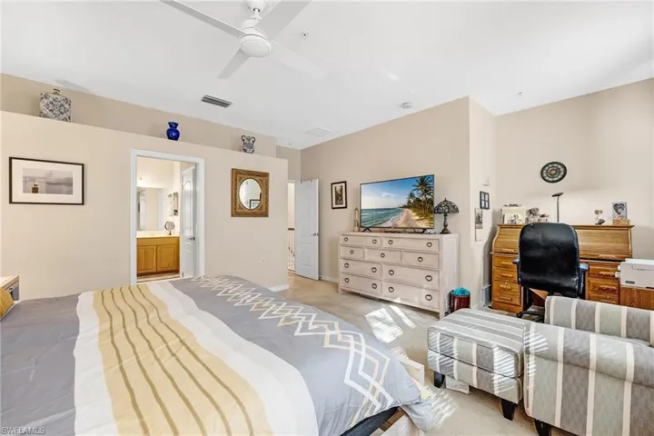Bedroom with light carpet, a ceiling fan, and ensuite bath