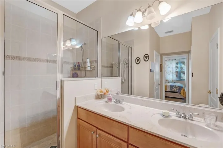 Ensuite bathroom featuring a shower stall and double vanity