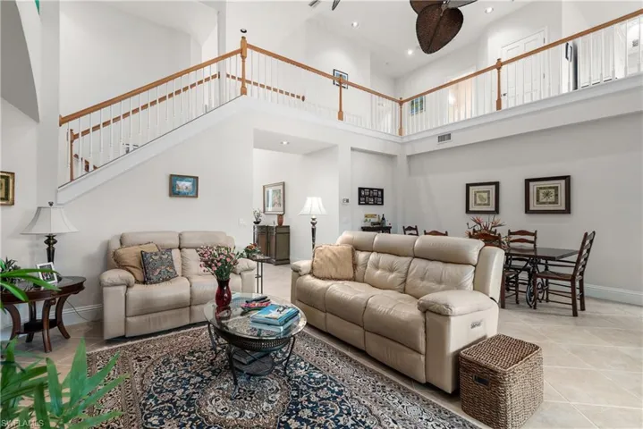 Tiled living room featuring ceiling fan and a high ceiling
