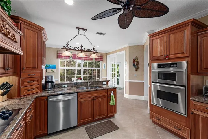 Kitchen with sink, stainless steel appliances, hanging light fixtures, and ornamental molding