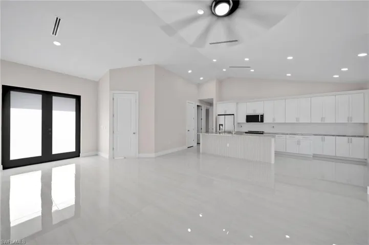 Unfurnished living room with recessed lighting, light tile patterned floors, high vaulted ceiling, a ceiling fan, and baseboards