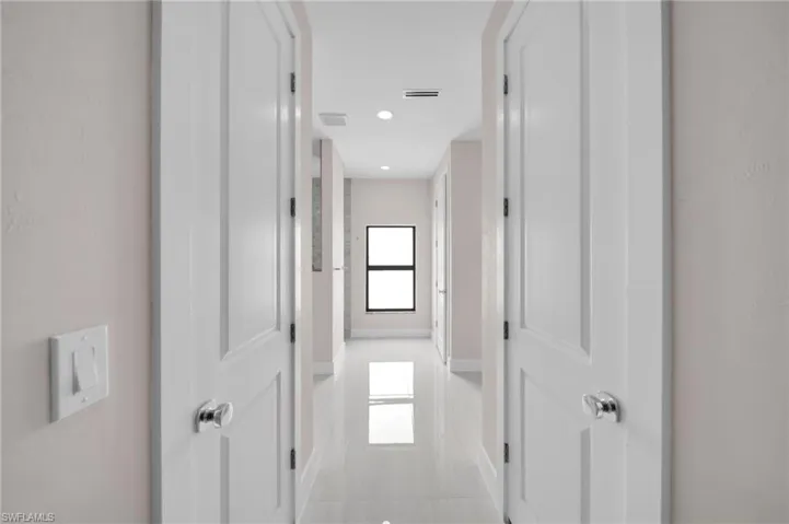 Hallway with light tile patterned floors, recessed lighting, visible vents, and baseboards