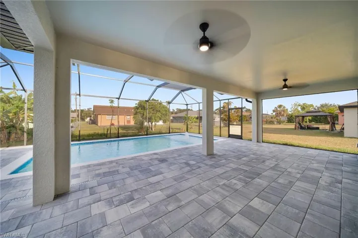 Pool with a patio, a ceiling fan, a yard, and glass enclosure
