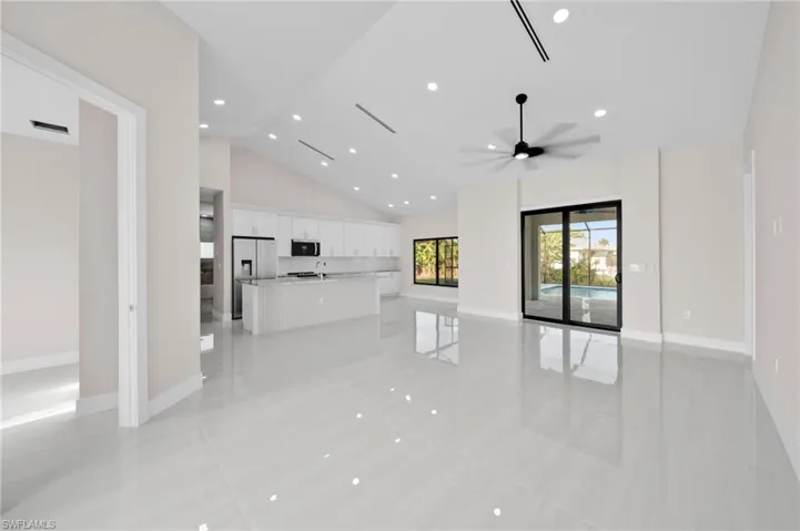 Unfurnished living room with light tile patterned flooring, a ceiling fan, high vaulted ceiling, and baseboards