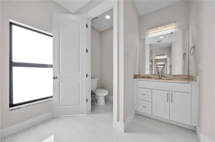 Bathroom with vanity, toilet, plenty of natural light, and baseboards