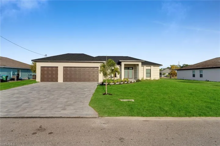 Prairie-style home with a front yard, decorative driveway, and a garage