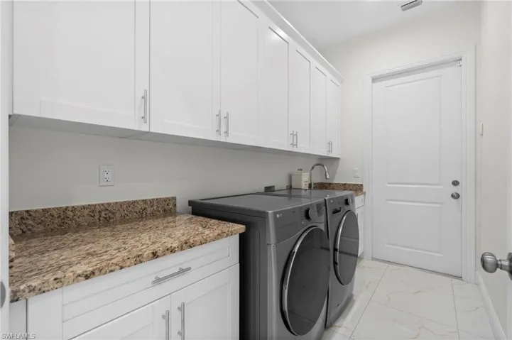 Laundry room with front load washer and dryer plus cabinet space with stone countertop!