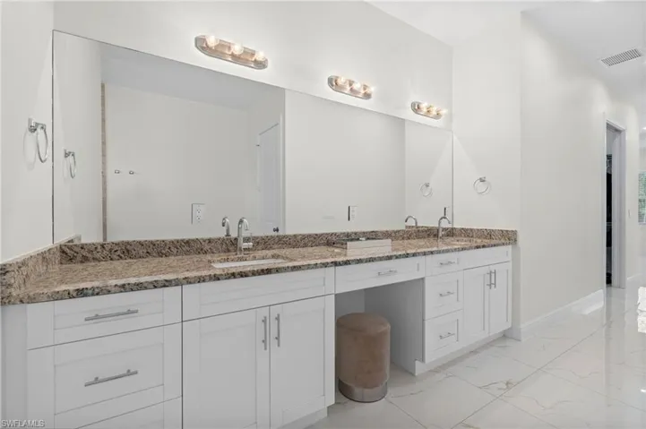 Bathroom featuring double vanity, visible vents, marble finish floor, and a sink