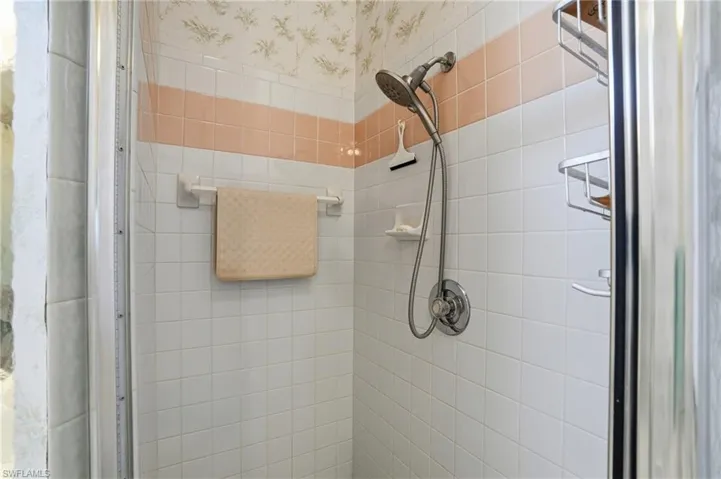 Bathroom featuring a shower stall and wallpapered walls