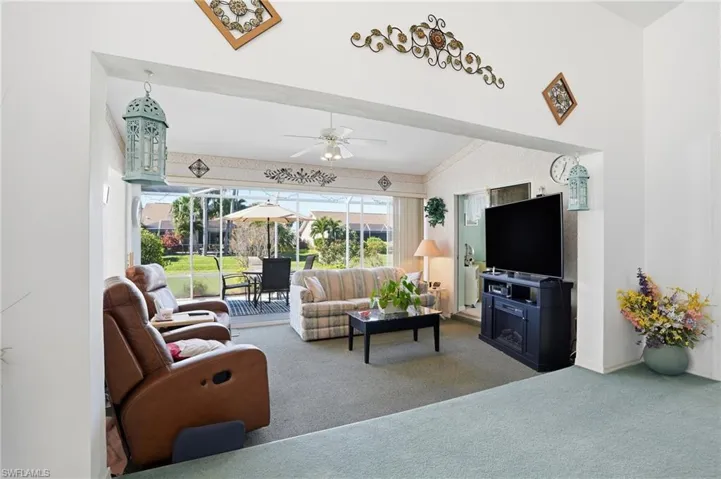 Living room with carpet, ceiling fan, and lofted ceiling
