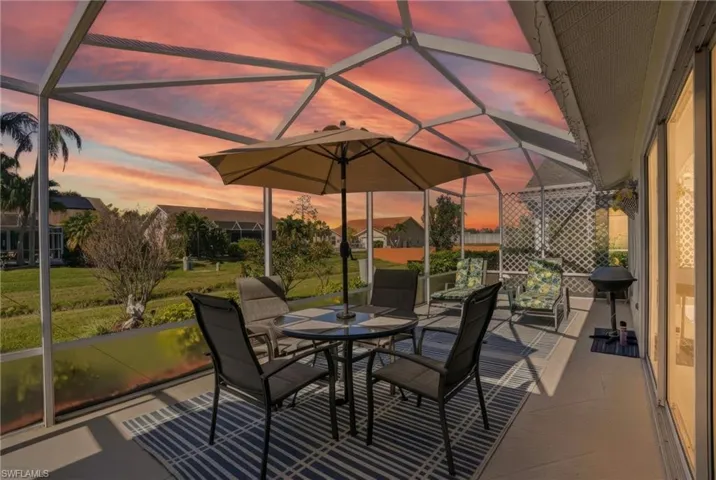 Patio terrace at dusk featuring a sunroom, a lanai, outdoor dining area, a patio area, and area for grilling