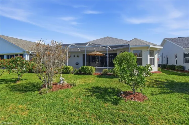 Rear view of property featuring a sunroom, a lanai, a yard, and stucco siding