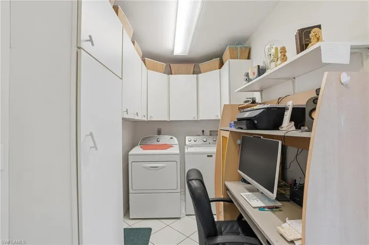 Office space with light tile patterned floors and washing machine and dryer
