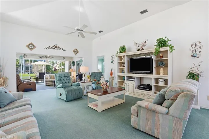 Carpeted living area with a towering ceiling and a ceiling fan