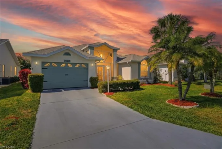 View of front of house with a lawn, driveway, stucco siding, and a garage