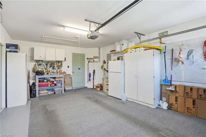 Garage with freestanding refrigerator, a garage door opener, and a workshop area