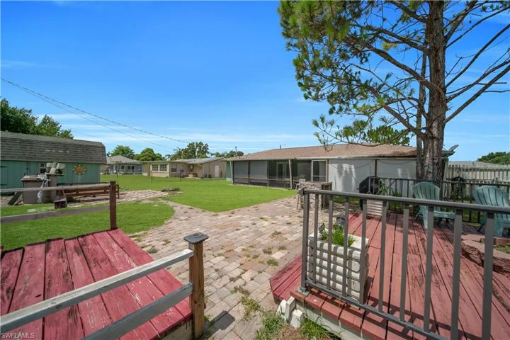 Expansive outdoor space featuring a paved patio, a stone-clad outdoor cooking station, and a fenced perimeter