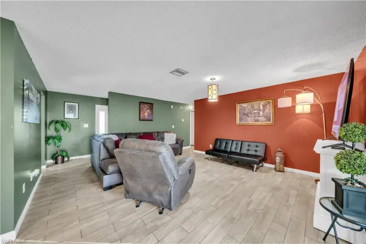 Living area featuring wood-finish flooring, a white mantel, and a wall-mounted television