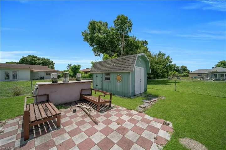 Expansive backyard featuring a lush lawn, a detached shed, a paved patio area, and a brick paver pathway